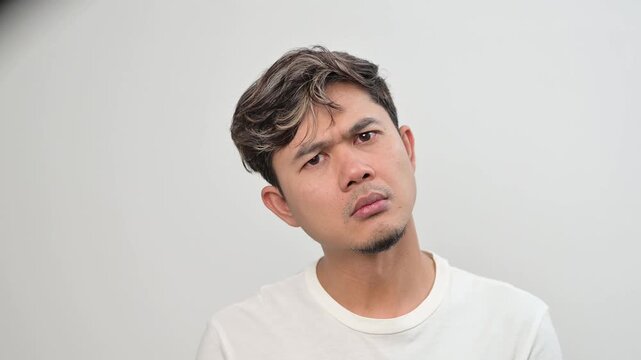 A video portrait of an adult Asian man with a perplexed and inquisitive expression. The concepts of doubt, curiosity, uncertainty, and problem awareness in daily life.