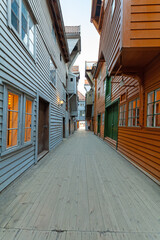 Summer day exploring behind facades in Bryggen Bergen, narrow lanes, colorful wooden buildings, historic trade stores, Vestland, Norway.