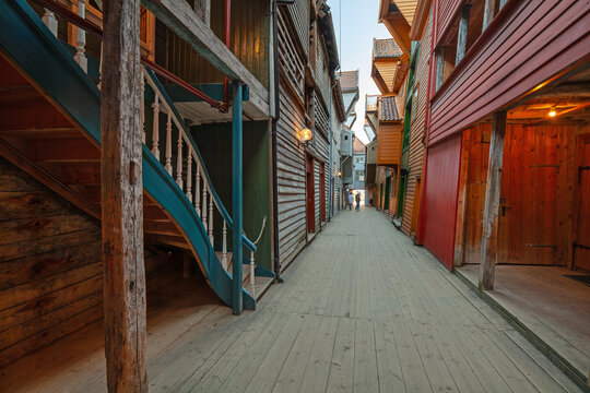 Summer day exploring behind facades in Bryggen Bergen, narrow lanes, colorful wooden buildings, historic trade stores, Vestland, Norway.