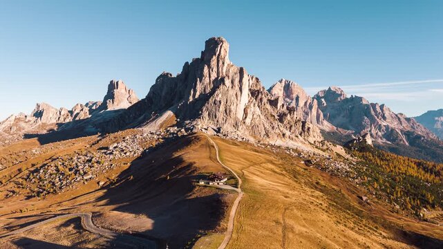 Sunrise over Passo Giau with Ra Gusela mountain peak, wooden lodge on golden hill in Dolomites, Italy