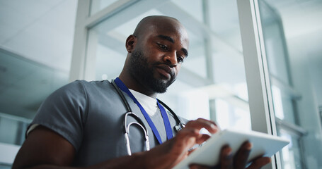 Black man, doctor and reading with tablet in hospital for research, medical report and test results. Below, male person and digital for healthcare history, treatment planning and surgery schedule