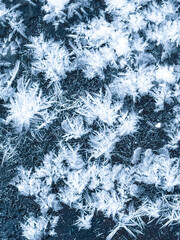 Abstract macro texture of large ice crystals and hoarfrost on a dark surface, beautiful winter rime patterns with sharp frozen details