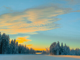 Dramatic Golden Sunset Cloud Over a Snow-Covered Field and Frozen Arctic Forest Line