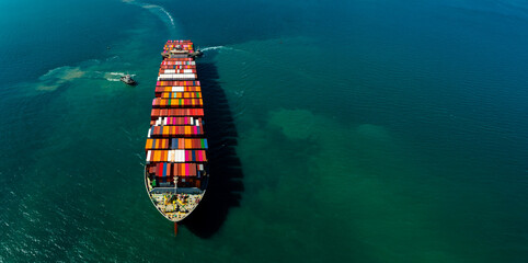 Aerial top view of tugboats assisting large cargo container ship for maritime business logistics and global international industrial import export freight transportation.
