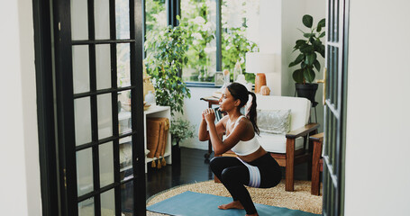 Obraz premium Squat, fitness and health with woman in home for workout, glute growth development or challenge. Exercise, wellness and muscle with person in living room of apartment for training and resistance band
