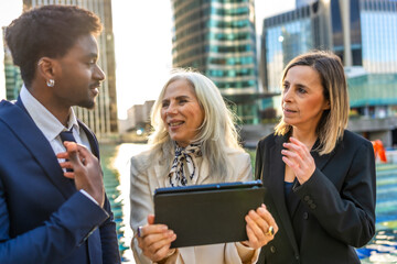 Diverse business team discussing strategy using tablet outdoor