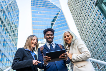 Diverse business team collaborating using tablet outdoors in city