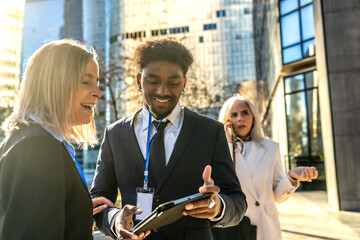 Diverse business team collaborating outdoors using digital tablet