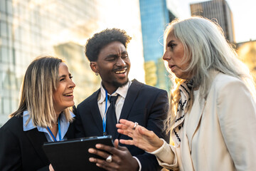 Diverse business team collaborating outdoors with digital tablet