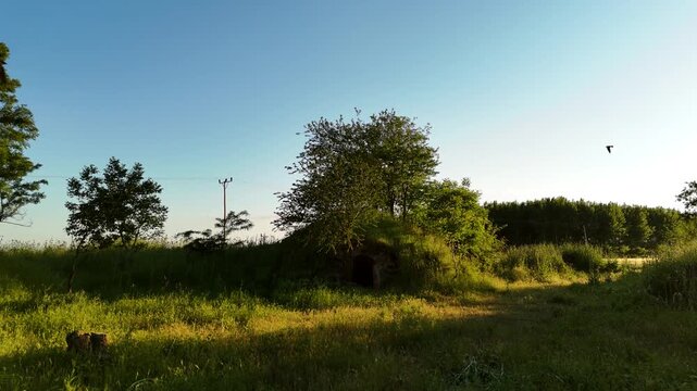 Discovering Fairy-Tale Earth Dwellings in Verdant Meadow &ndash; Low Altitude Drone Footage, Serene Nature & Sun Reflections