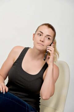 Studioaufnahme einer jungen Frau, die sitzend telefoniert und dabei nachdenklich wirkt. Der helle, neutrale Hintergrund und die ruhige K&ouml;rpersprache vermitteln Alltag, Kommunikation und emotionale Sit