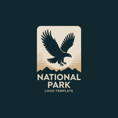 Obraz premium This logo features a majestic eagle in mid-flight above a mountain range, embodying the essence of the wilderness and adventure associated with national parks.