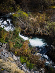 A scenic view of a cascade flowing down rocky hill with lush green vegetation. High quality photo