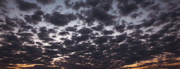 the evening sky is a beautiful blend. of blue sunlight and an orange horizon, with soft, fluffy clouds.