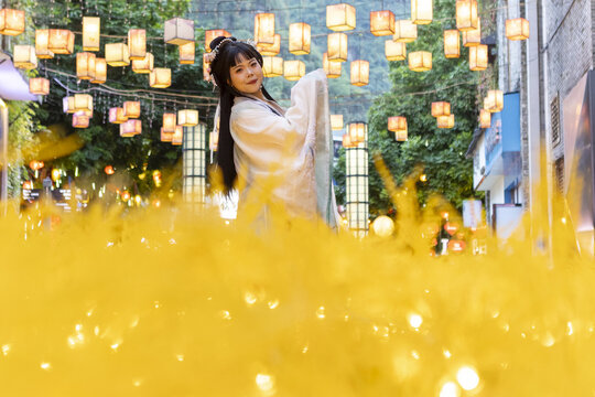 View of a woman in traditional white dress among warm glowing lanterns, a cultural dance in the vibrant city, Guilin, Guangxi, China.