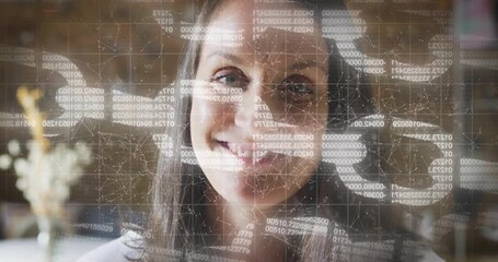 Mid adult woman sitting in office, grid overlay appearing, code scrolling, smiling, analyzing data - Powered by Adobe