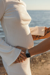 Close-up of pregnant belly on the beach. Vertical image