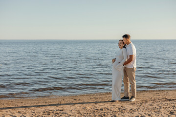 Happy young couple on the beach. Pregnant woman and man on a walk. Family expecting a child.