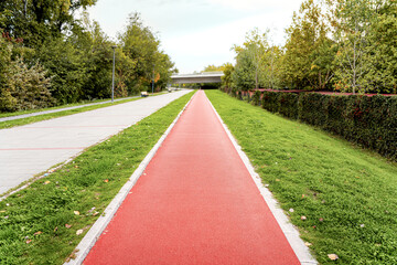 Red rubber recreational jogging path in city. Sports urban infrastructure.