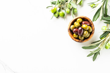 Olives in the bowl at white table.