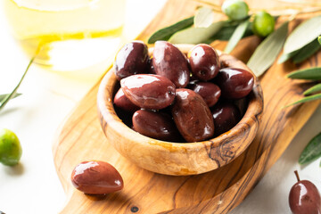 Olives in the bowl at white table.
