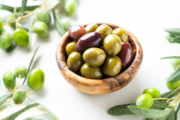 Olives in the bowl at white table.