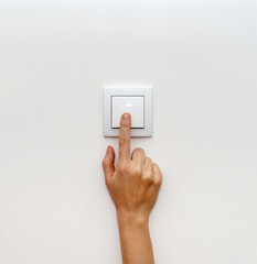 Female hand turning off light switch for energy saving.