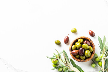 Olives in the bowl at white table.