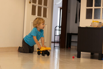 Toddler boy playing with toy dump truck on floor