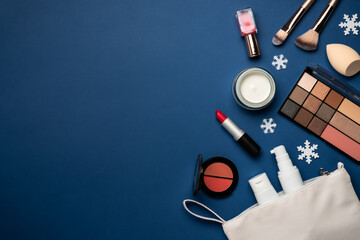 Face cream, make up shadows, lipstick, cosmetic brushes on blue background.