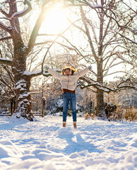 Young woman enjoying winter outdoors, jumping exuberantly in city park