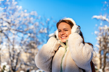 Portrait of young woman in cozy winter clothes enjoying cold season outdoors