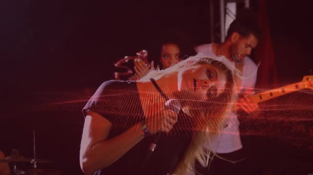 Camera rising, singer moving and singing on stage, red wave sweeping across band boosting energy