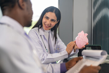 Doctors discussing cardiology case using heart model and digital scan, cardiovascular health, medical training and heart anatomy explanation, modern medical training team education, heart disease