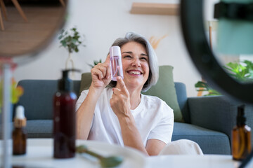 Happy woman presenting toner bottle during beauty tutorial at home