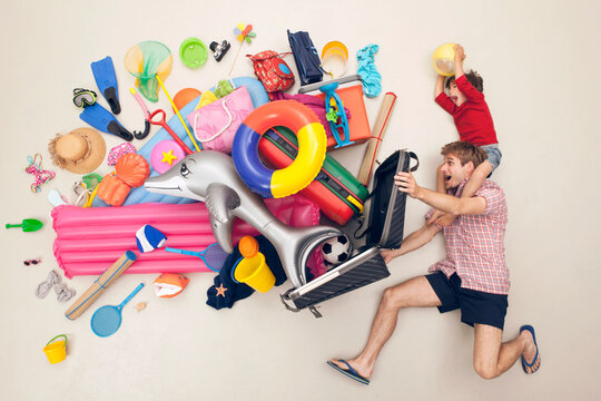 Father and son playfully spilling vacation luggage in studio