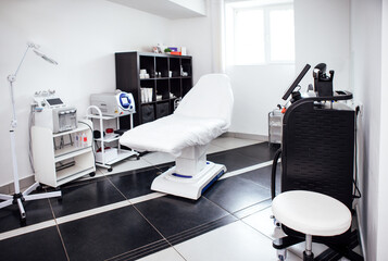 Clean and modern medical treatment room featuring an adjustable examination table, medical equipment, and a comfortable chair, designed for patient care and wellness services