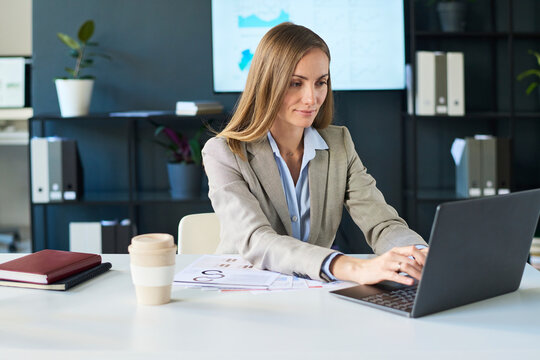 Businesswoman working on laptop at office desk with business documents