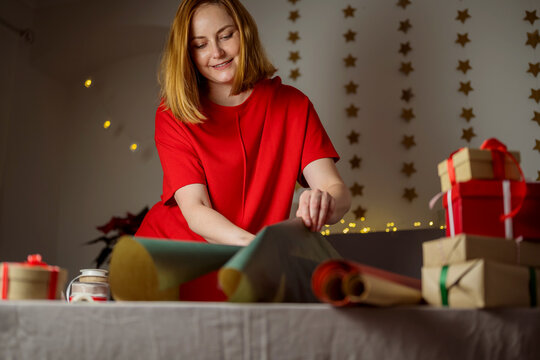 Smiling woman wrapping Christmas gifts in a festive home setting