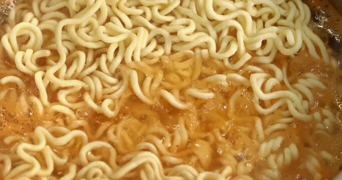 Instant noodles are poured into boiling water, the process of cooking Korean spicy instant noodle soup ramyong.