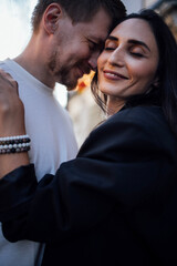 Couple embracing outdoors, sharing a joyful moment, with soft sunlight illuminating their faces, showcasing love and connection in a candid, intimate setting