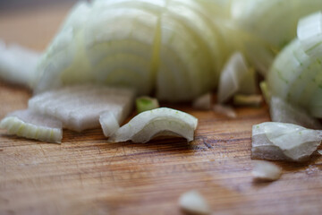 Close up of chopped white onion pieces on wooden cutting board. Raw vegetable ingredient preparation texture.