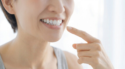 白い歯と美しい歯並びを指さす女性　