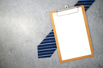 Clipboard with necktie on stone texture background. Business desk office. Top view