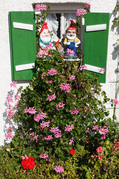 Garden gnomes and pink flowers at a window in We�ling Upper Bavaria