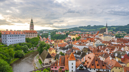 Fototapeta premium Visitors walk through the winding streets of Cesky Krumlov in summer. The colorful buildings and historic architecture create a lively atmosphere by the river.