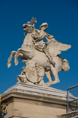 Obraz premium Paris - France - 01 07 2026: Snow flakes. View statue Mercury of Coysevox in Tuileries garden under the snow and sunny blue sky