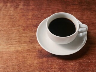 Black coffee in a white ceramic cup on a rustic wooden table background with copy space. Perfect for themes of morning routine, break time, caffeine, breakfast, and cafe lifestyle