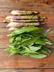  A harvest of spring greens, wild garlic and asparagus lie on a wooden table.