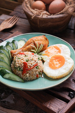 Nasi Goreng served with fried egg fried chicken and fresh cucumber ulam is a classic Southeast Asian meal combining savory flavors, crispy textures, and traditional home cooked comfort food.